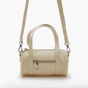 Cream mini cylinder bag‎ with silver hardware, featuring a zip closure